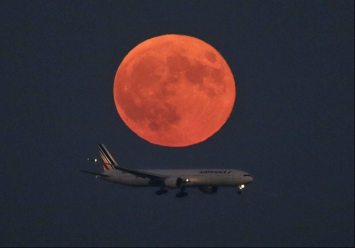 Foto sacada desde el aeropuerto de Tokio, Japón, con el avión de Air volando bajo la Luna roja del 28 de septiembre de 2015.