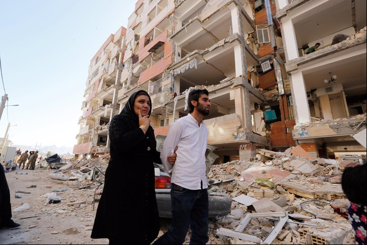 Una pareja camina entre los restos de los edificios en la zona afectada por el terremoto que asoló en noviembre la ciudad de Pole-Zahab (Irán). EFE