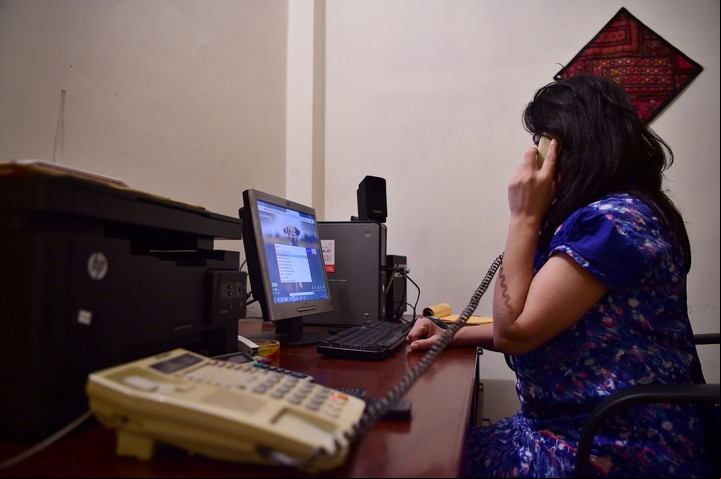 Ayeesha, que trabaja en la ONG paquistaní Aware Girls, habla con una mujer que llamó a la línea directa "Sahailee". / AFP