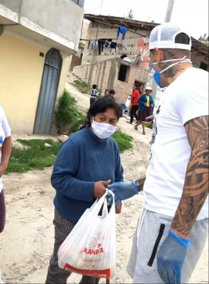 Gerardo Martínez le entrega una bolsa con comida a una señora de uno de los barrios que visitó en Cajamarca, Perú.