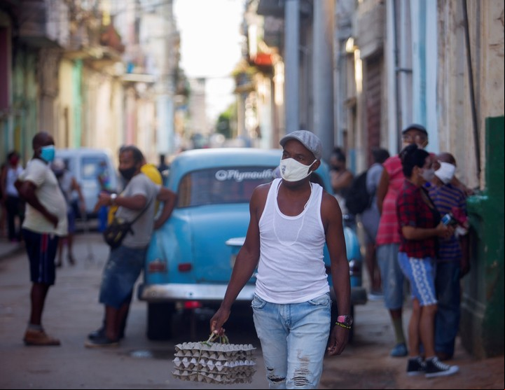 Un hombre camina por una calle con cubetas de huevos en La Habana. Foto EFE