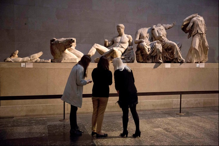 Las mujeres de pie junto a una estatua de mármol de un joven desnudo cree que representa dios griego Dionysos, centro, desde el frontón este del Partenón, en la exhibición durante una oportunidad de fotos de los medios de comunicación para promover una próxima exposición sobre el cuerpo humano en el arte griego antiguo en el Museo Británico de Londres, jueves, 8 de enero 2015. (AP Photo/Matt Dunham, Archivo) / Archivo Clarín