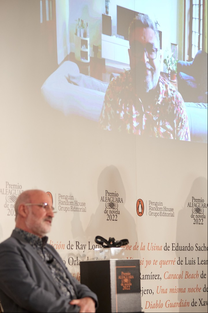 Fernando Aramburu dialoga con Cristian Alarcón (en pantalla) en la ceremonia de anuncio del Premio Alfaguara de Novela. Foto EFE/ Miguel Osés