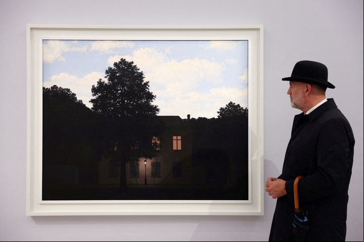 FOTO DE ARCHIVO: Un empleado de Sotheby's posa con la obra de arte 'L'empire des lumieres, 1961' de Rene Magritte, expuesta antes de su subasta en Sotheby's en Londres, Gran Bretaña, 22 de febrero de 2022. REUTERS/Tom Nicholson