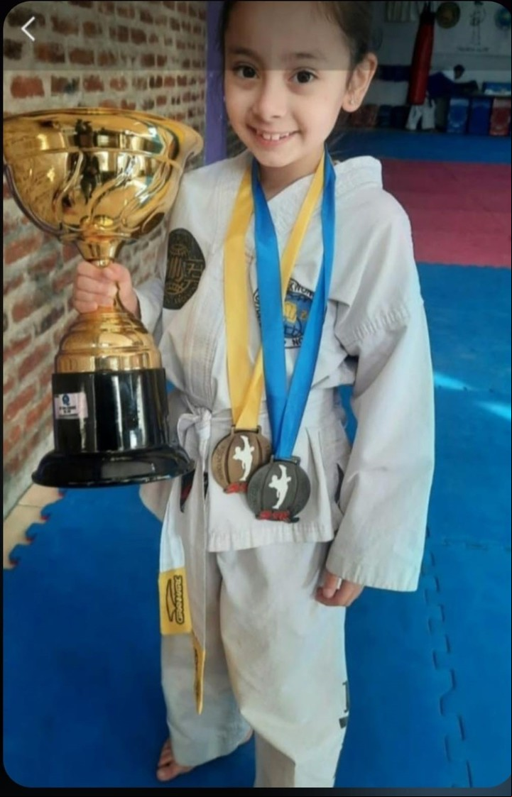 Uma con sus trofeos y medallas en artes marciales.