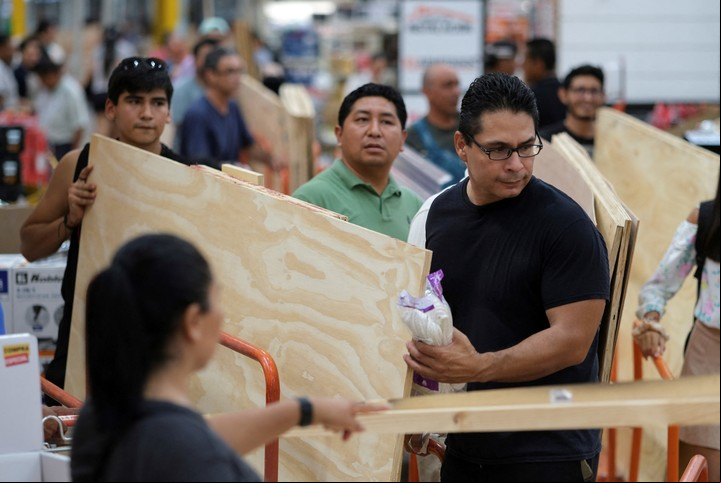 La gente compra maderas para proteger puertas y ventanas durante el huracán. Foto: Reuters