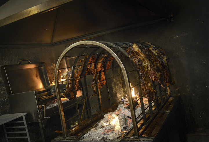 Las jaulas cocinan las carnes en el patio de Todo Brasas. Foto: Constanza Niscovolos.