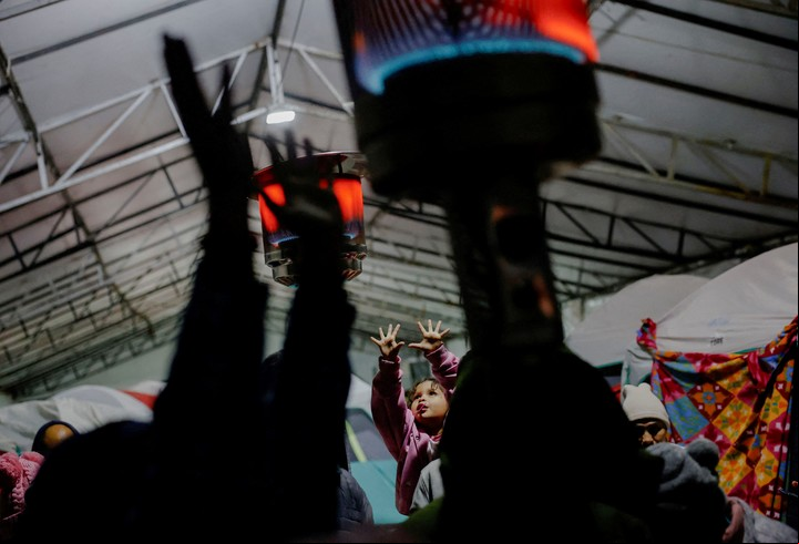 Solicitantes de asilo, en su mayoría con citas canceladas de CBP One, se calientan junto a calentadores de gas debido a las bajas temperaturas, mientras esperan en un refugio temporal con la esperanza de una nueva oportunidad para entrar a Estados Unidos el día de la toma de posesión del presidente estadounidense Donald Trump, en Matamoros, México 20 de enero de 2025. REUTERS/Daniel Becerril