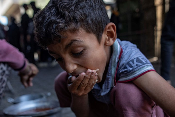 Un niño desplazado palestino come en una cocina comunitaria en Gaza. Foto: EFE