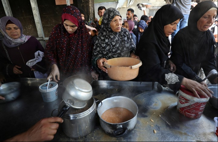 Palestinos hacen fila para recibir un plato de comida. Foto: Reuters